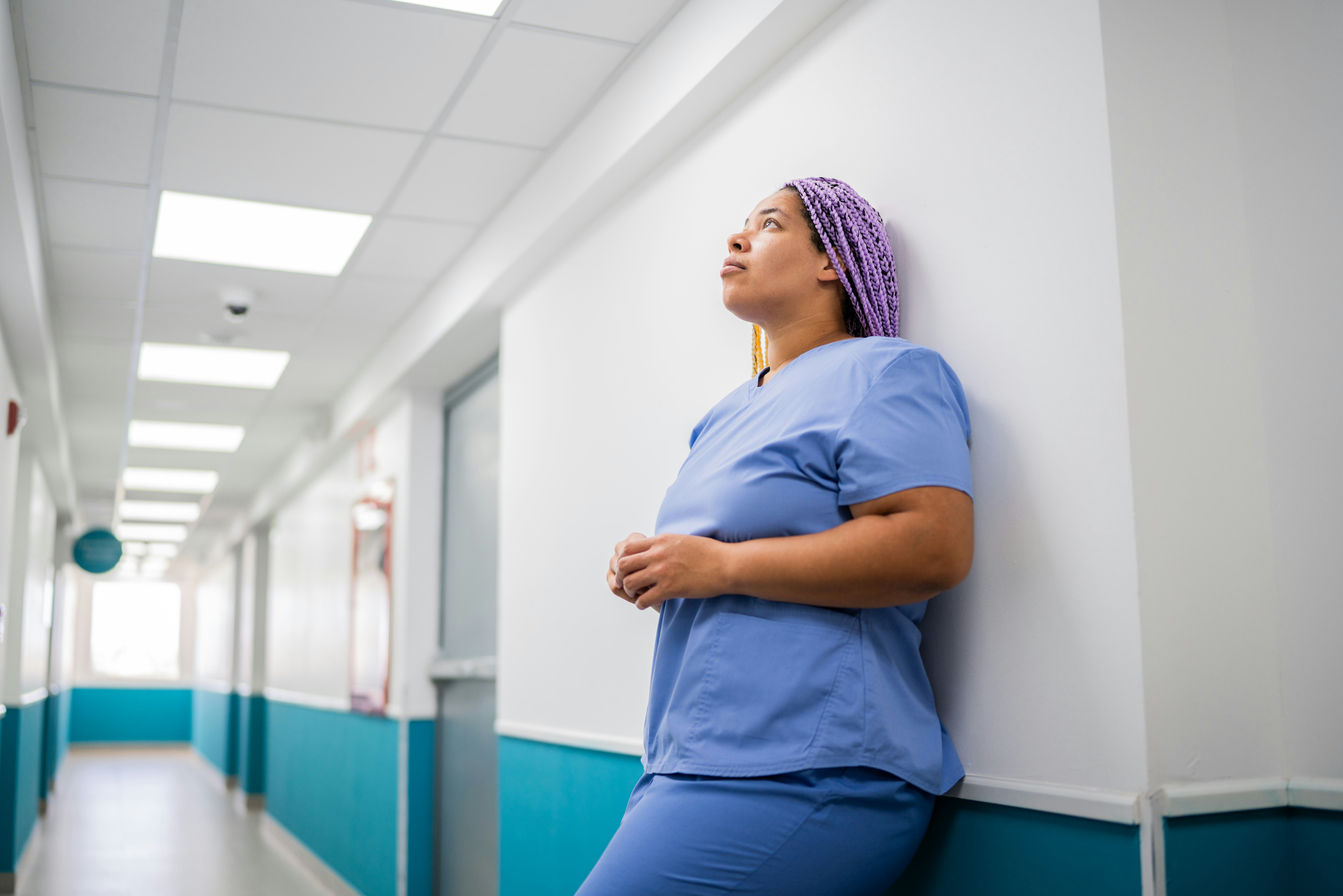 Worried mid adult nurse woman on corridor at hospital