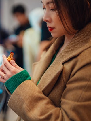 Young woman trying lipstick on hand at cosmetic store in a story about the best new beauty products ...