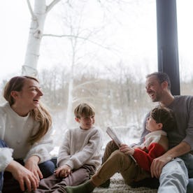 Photo of a cheerful young family, sitting in their cosy home, reading books and enjoying each others...