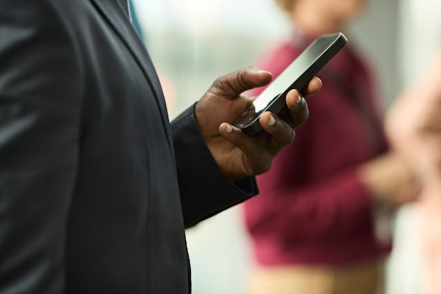 Midsection of businessman scrolling smart phone in seminar