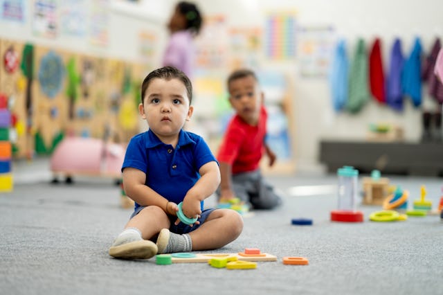 Diverse preschool scene shows curious children exploring shapes and colors with supervision, fosteri...