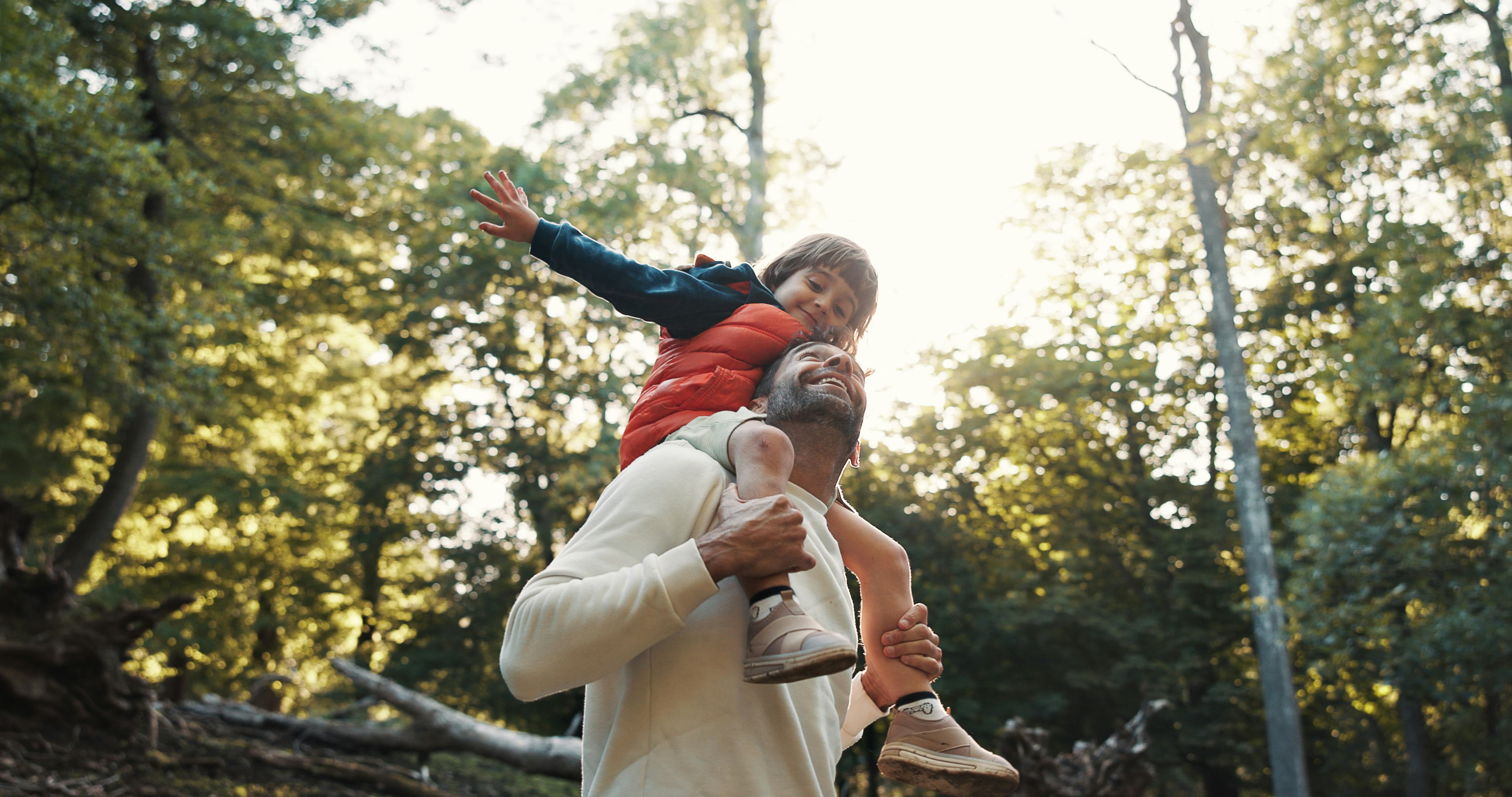 Happy dad, kid and shoulder with trees in nature for childhood, weekend or outdoor holiday. Father, ...