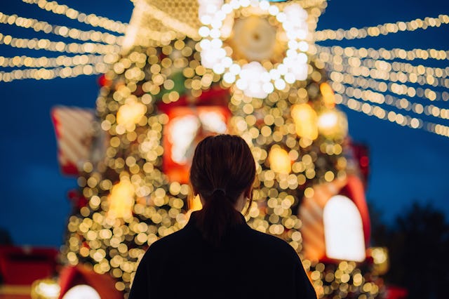 Rear view of young Asian woman looking at an illuminated Christmas tree with decorated Christmas lig...