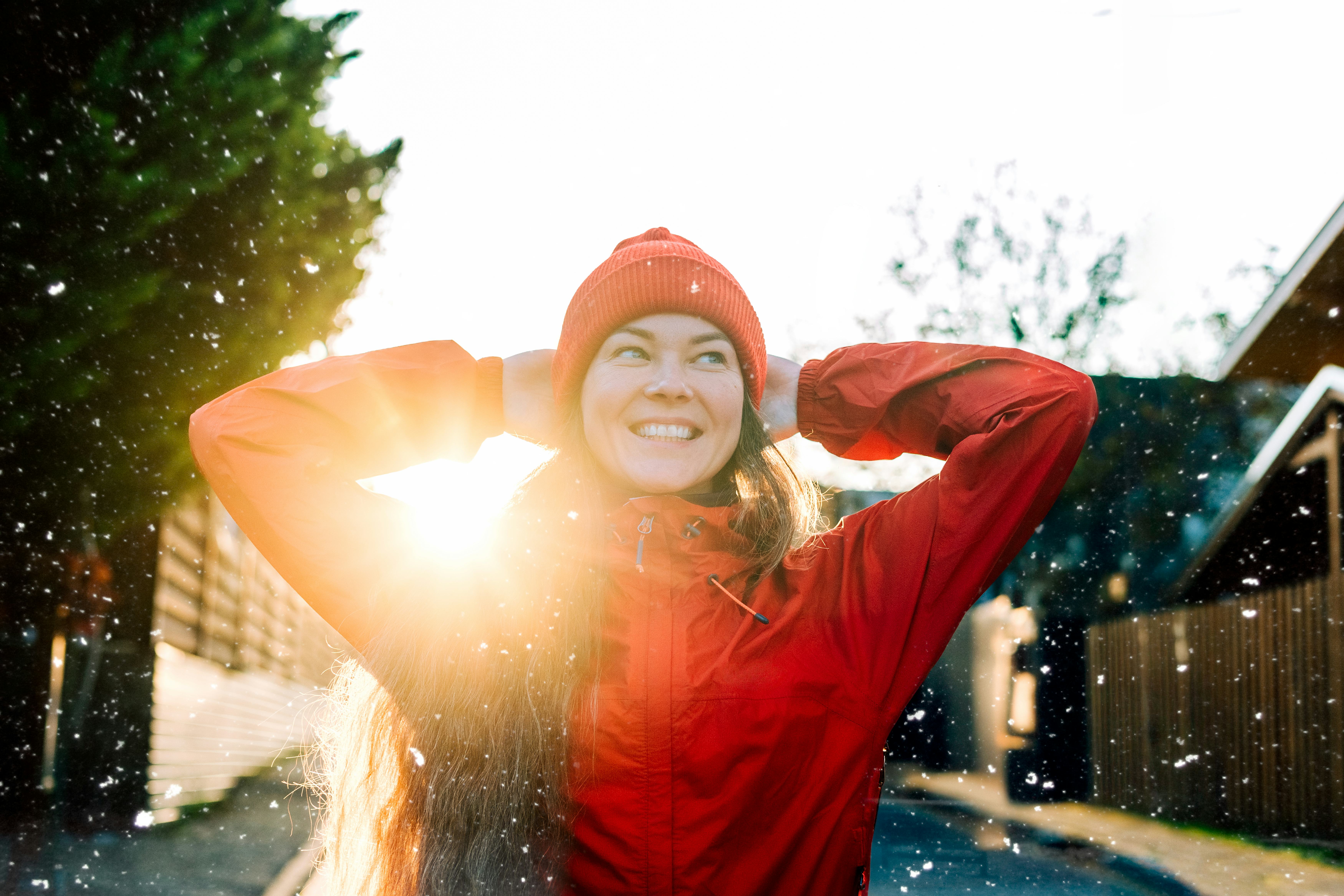 Woman enjoying sunny winter day with falling snow