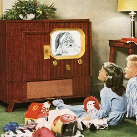 Boy and girl happily watching Santa Claus on television on Christmas day; photograph, 1950. (Photo b...