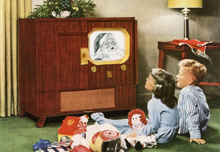 Boy and girl happily watching Santa Claus on television on Christmas day; photograph, 1950. (Photo b...