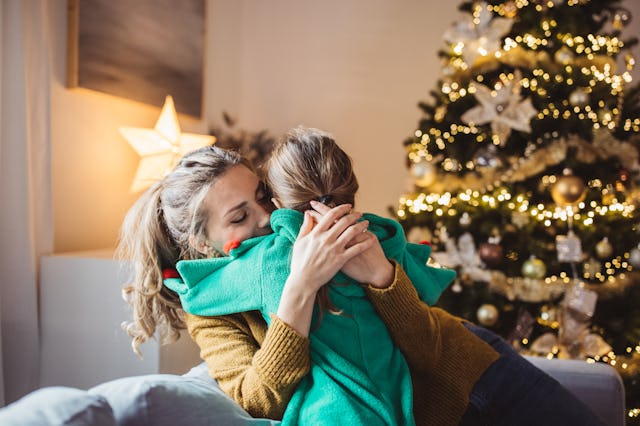 Little girl and her mom on Christmas morning at home. Girl is sad about something and mother is hugg...