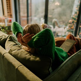 Photo of a young woman relaxing in her living room; staying in her warm and cozy home and enjoying t...