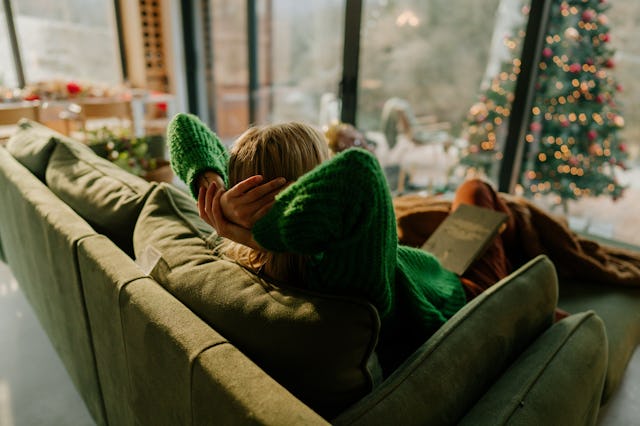 Photo of a young woman relaxing in her living room; staying in her warm and cozy home and enjoying t...