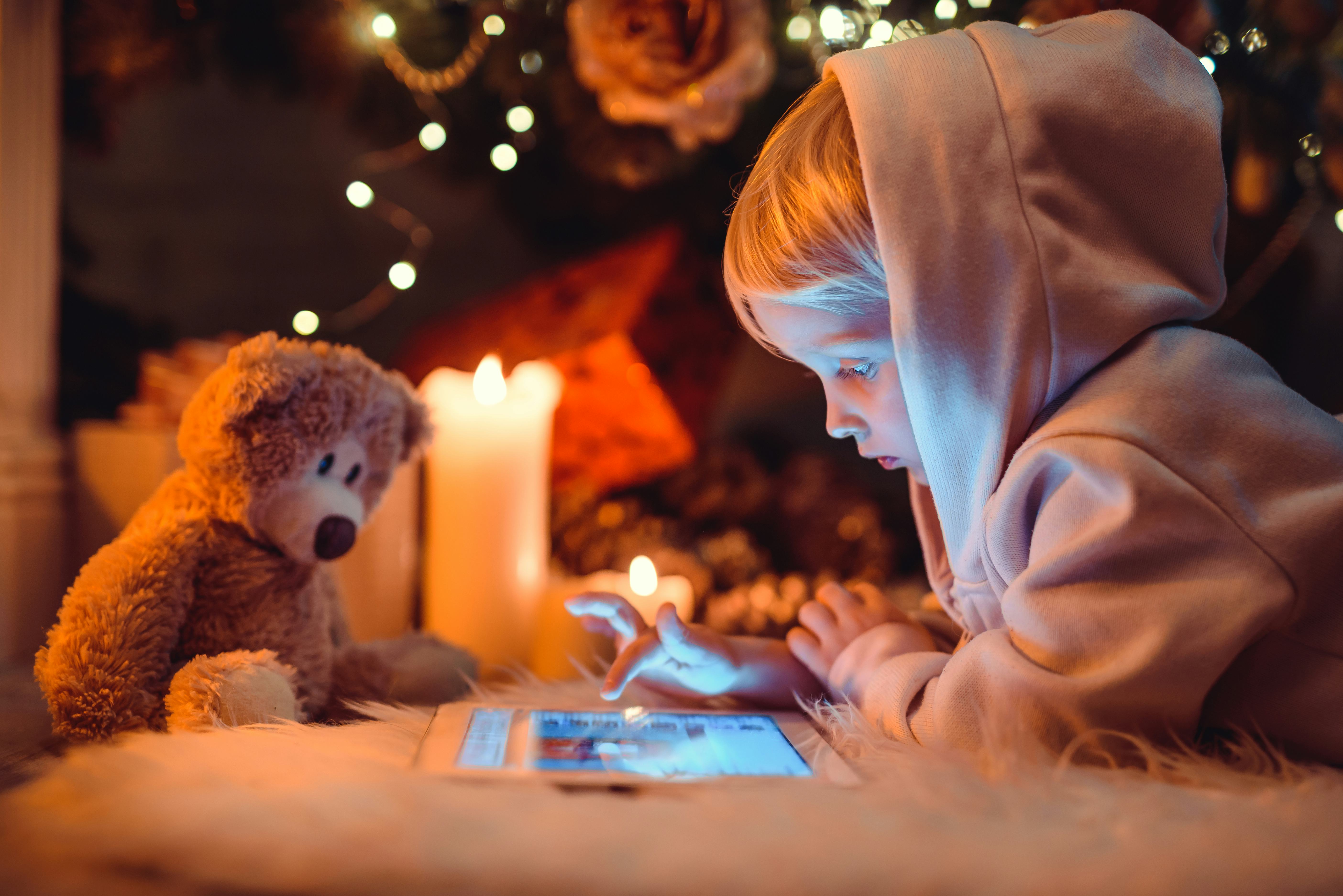 Little boy using tablet computer near fireplace. Christmas time.