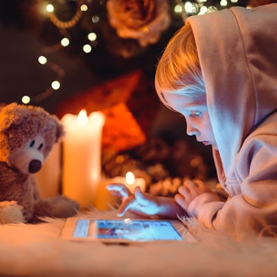 Little boy using tablet computer near fireplace. Christmas time.