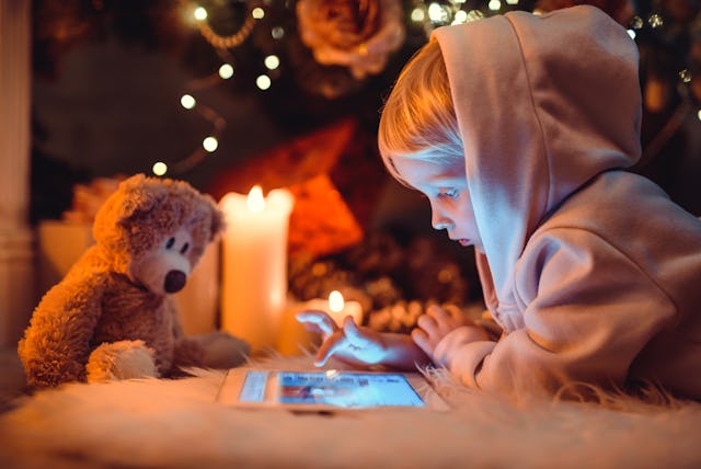 Little boy using tablet computer near fireplace. Christmas time.