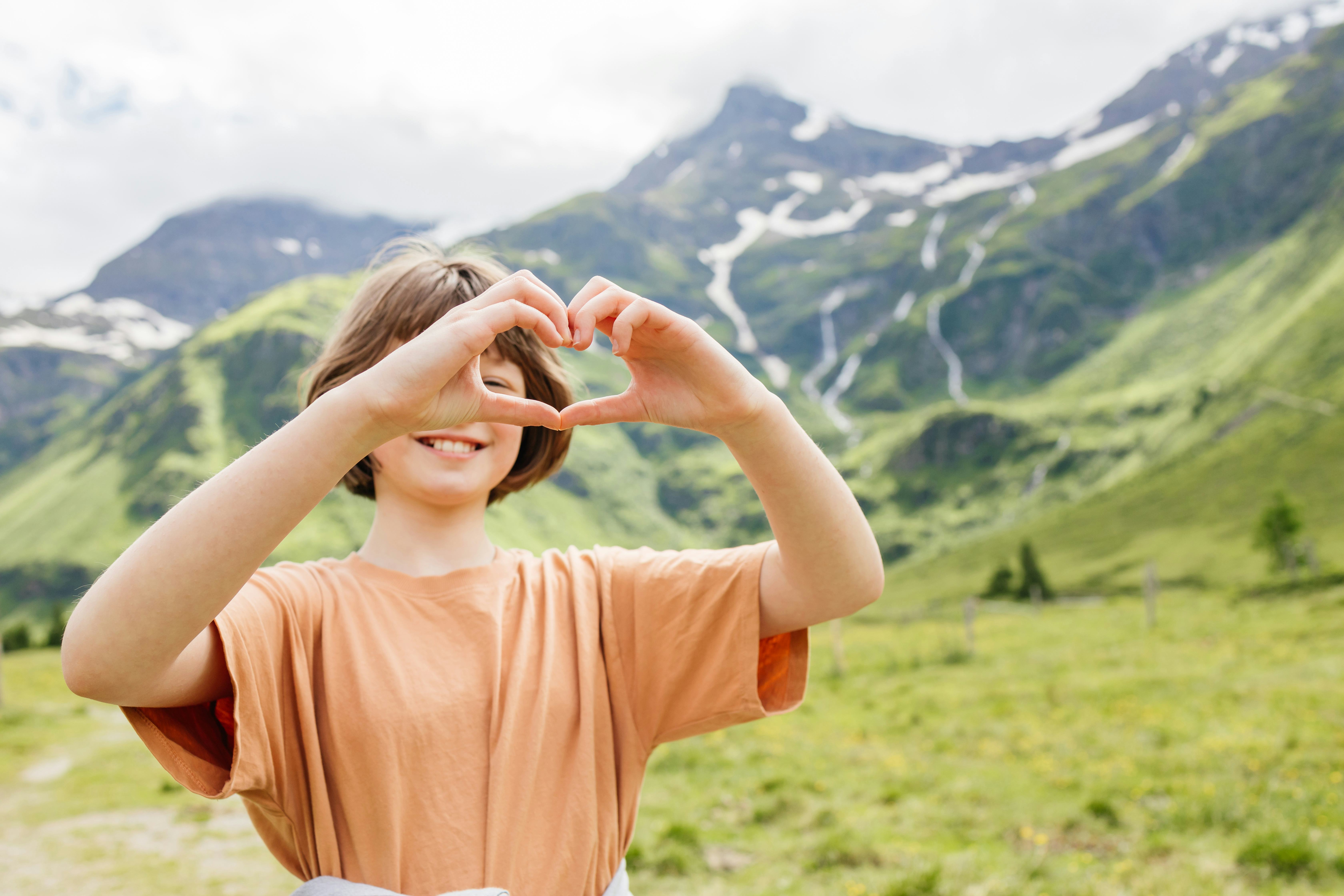 Happy child showing love for nature while enjoying summer vacation in the Swiss Alps.