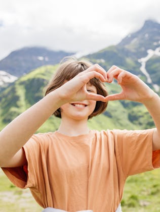 Happy child showing love for nature while enjoying summer vacation in the Swiss Alps.