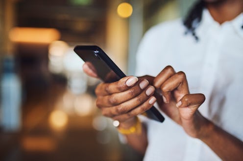 Extreme close-up shot of an African American woman's hands tapping and scrolling on a modern smartph...