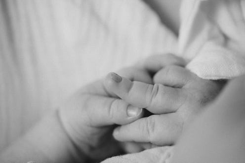 Parent hand gently holding baby finger, showing tenderness and love