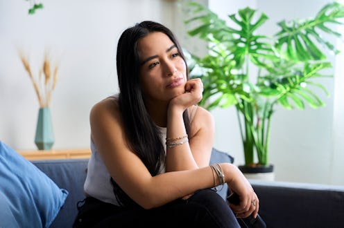 Young woman contemplating ideas while sitting on sofa at home