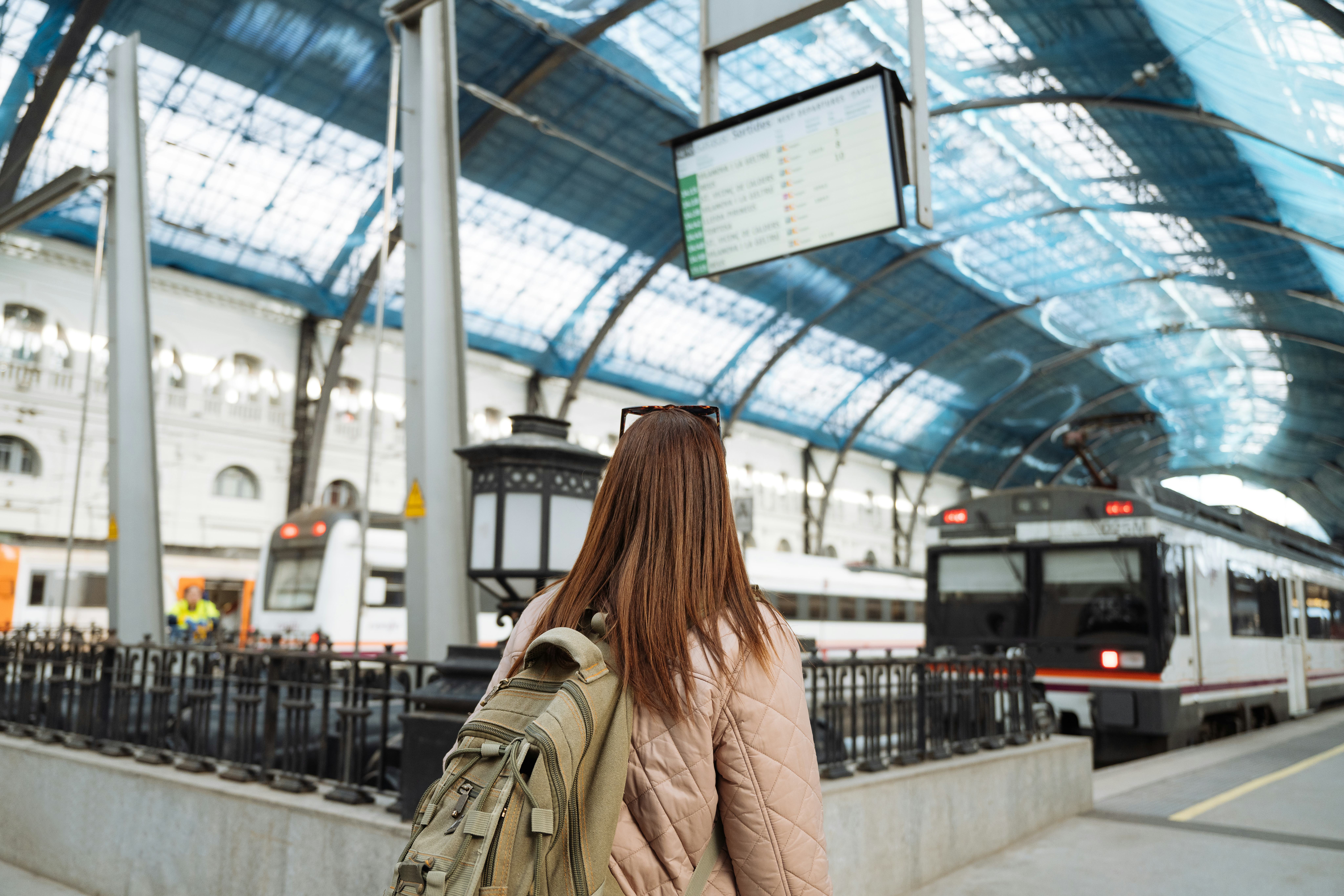 Single female traveler on train station with backpack, enjoying city break