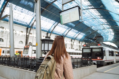 Single female traveler on train station with backpack, enjoying city break