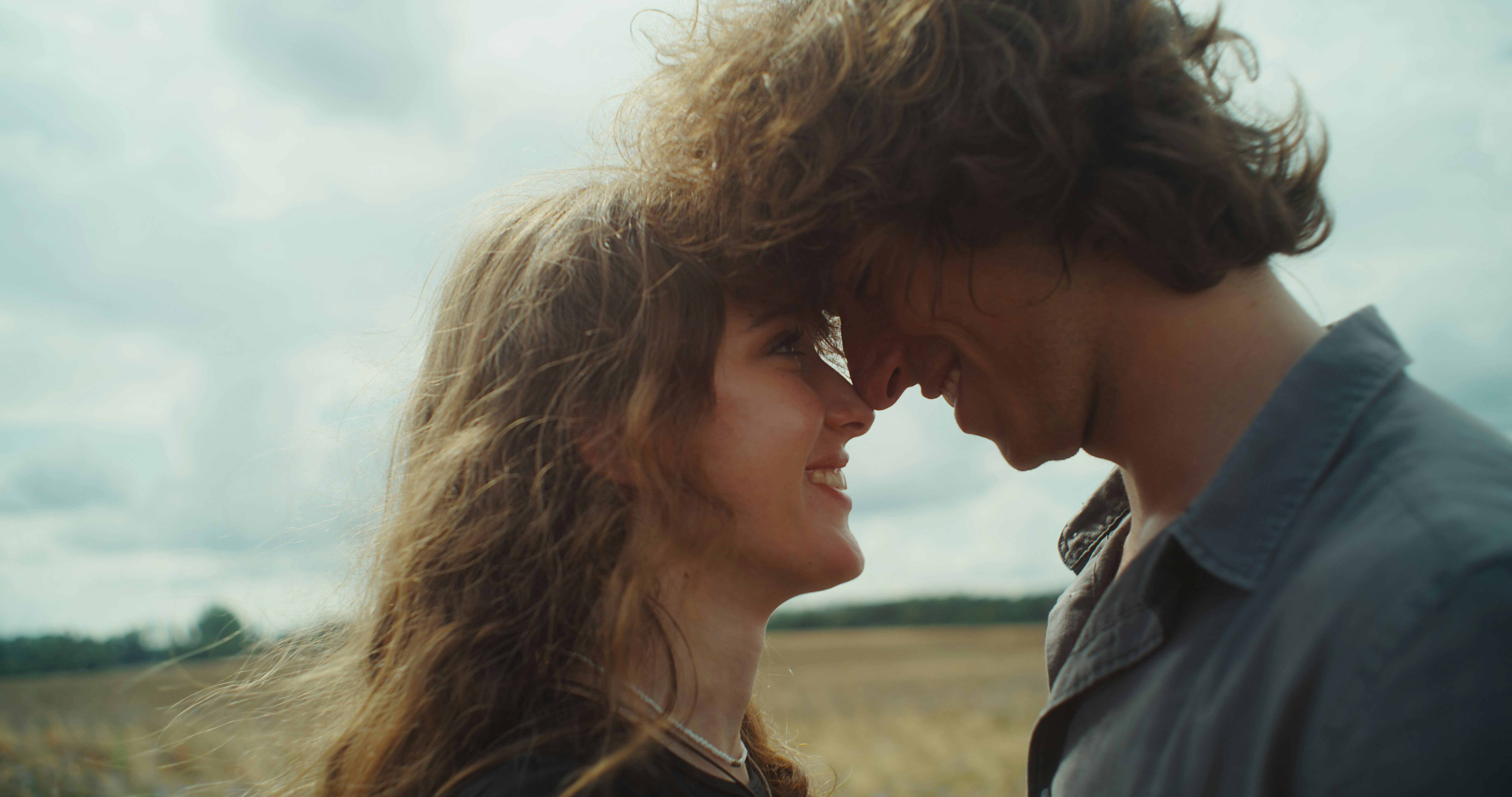 Beautiful sunny meadow in the heat of summer. Romantic couple man and woman embracing in the tall gr...