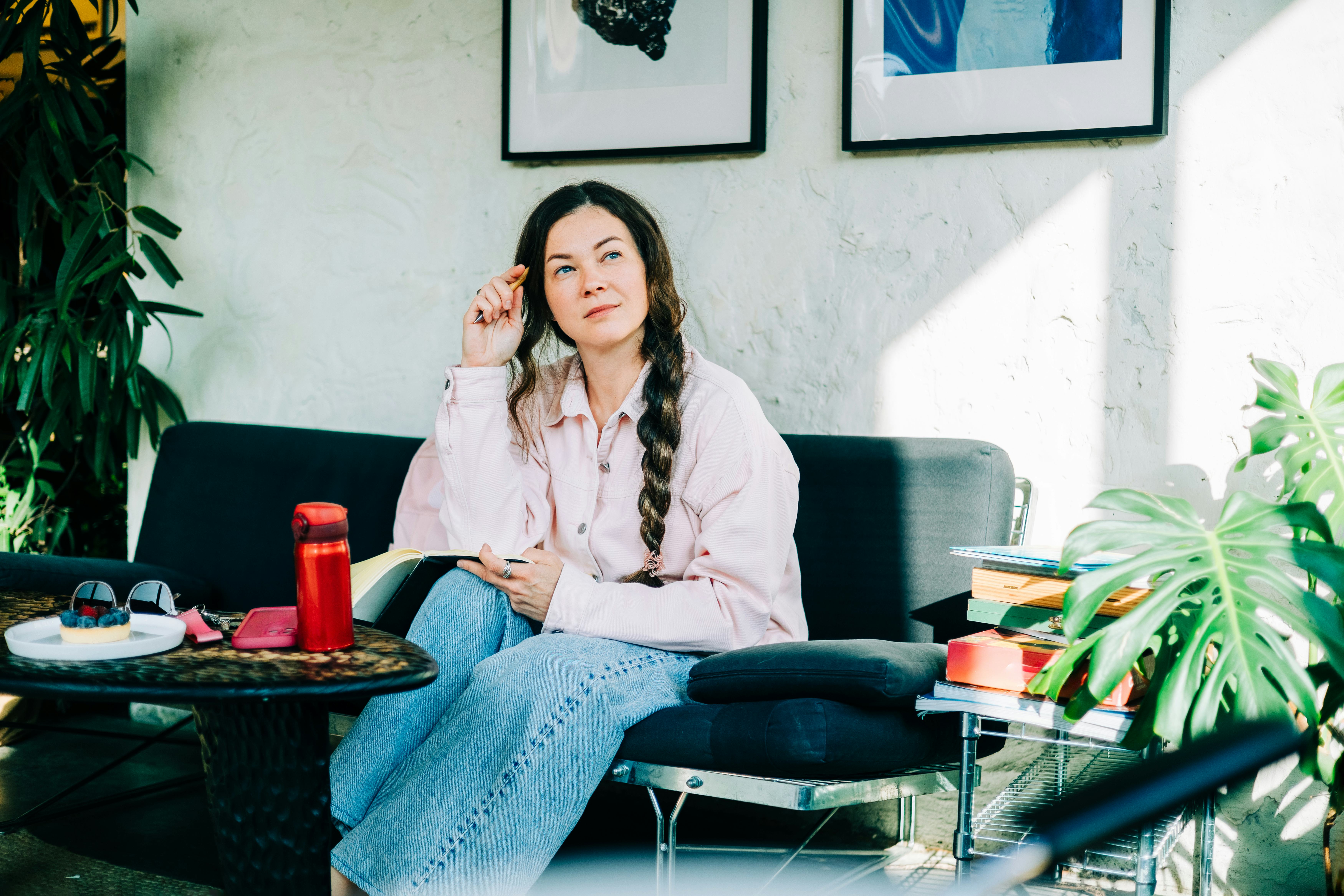 Woman thinking while writing in journal at cafe