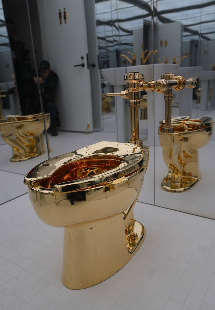 NEW YORK, UNITED STATES - NOVEMBER 17: Maurizio Cattelan's influential artwork, a solid gold toilet,...
