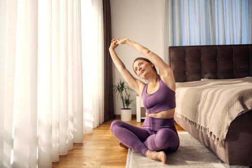 Woman warming up body and mind with yoga stretch in sunlit bedroom for fitness and healthy lifestyle