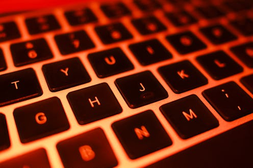 A close-up of a laptop keyboard with intense red lighting, creating a technological and futuristic a...