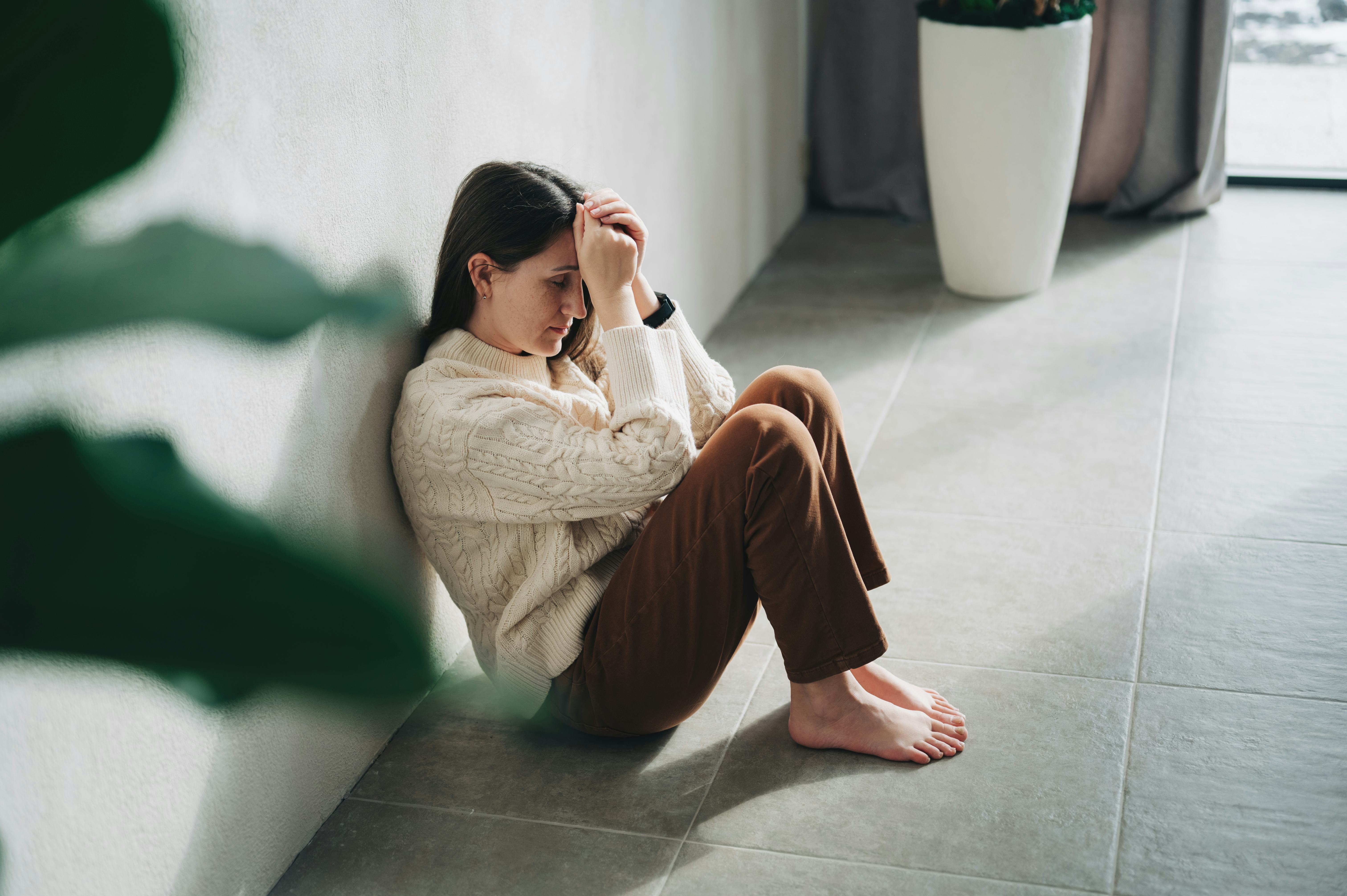 Silhouette of sad and depressed woman sitting on the floor at home