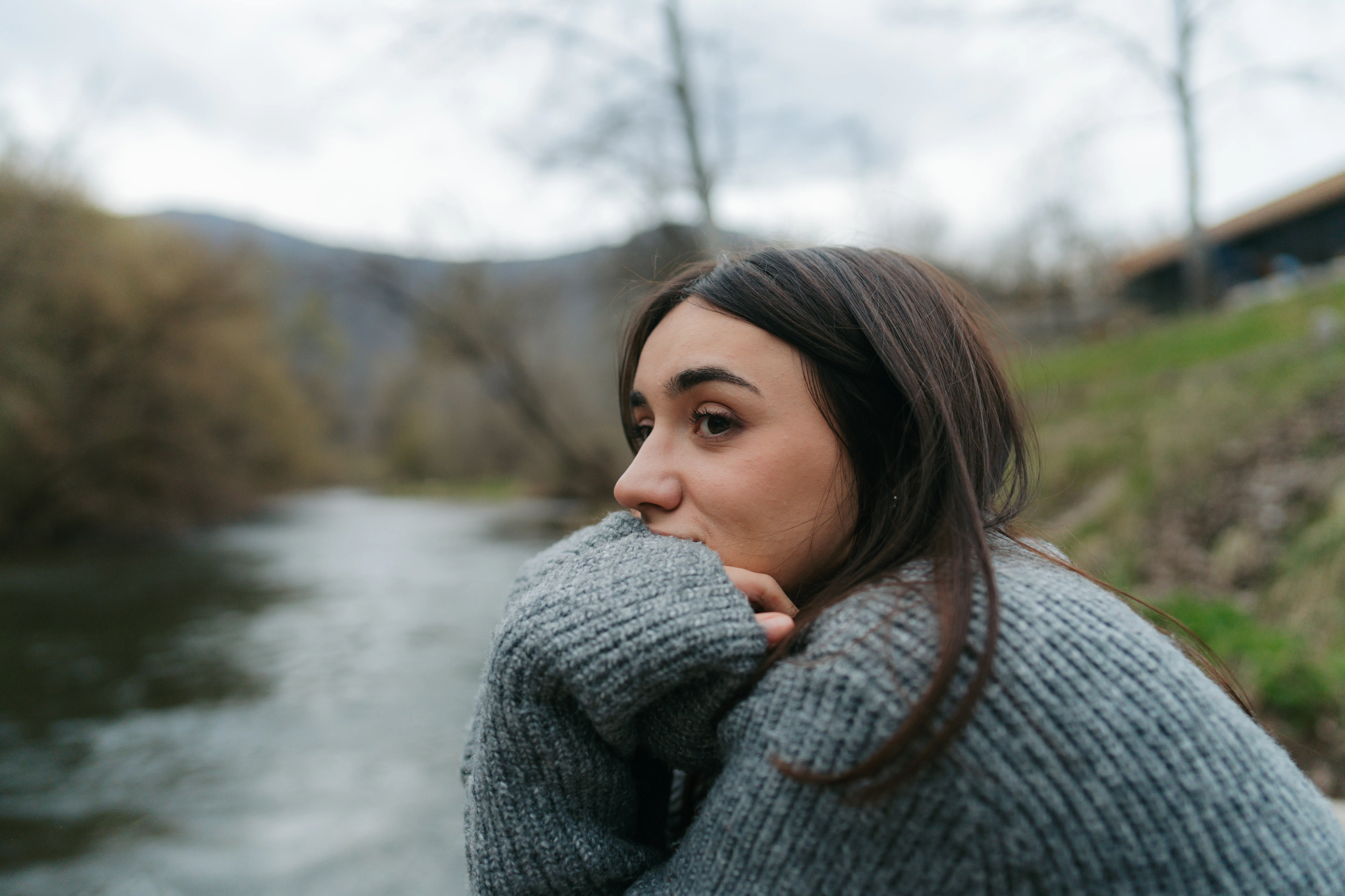 Portrait of a beautiful young woman, sitting on a riverside dock, enjoying the calm of nature at aut...