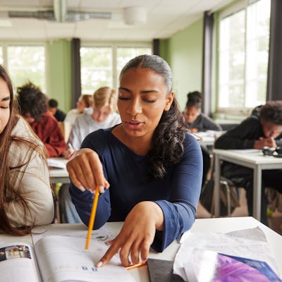 Two girls do paperwork in class.