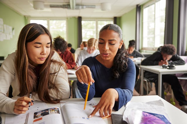 Two girls do paperwork in class.