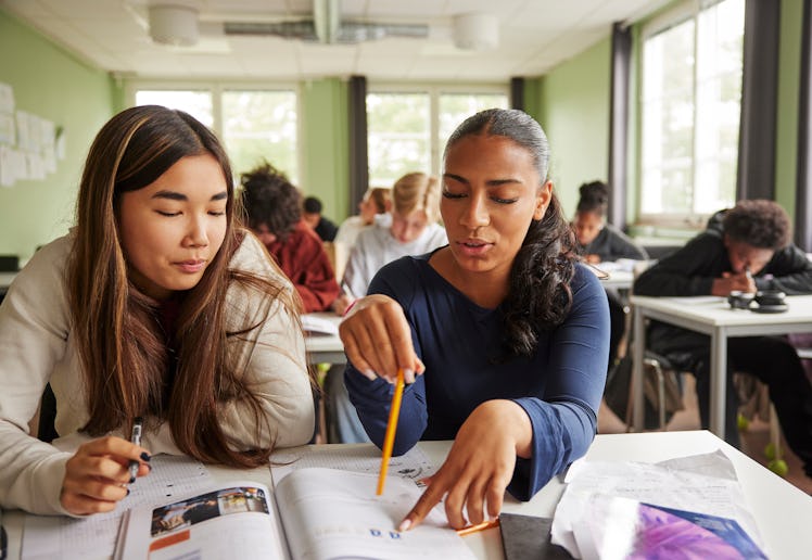 Two girls do paperwork in class.