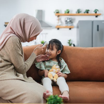 A woman uses a digital thermometer to check the temperature of her daughter. A doctor ranked the best types of thermometers to use for kids.