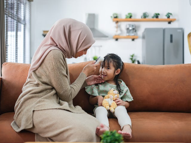 A woman uses a digital thermometer to check the temperature of her daughter. A doctor ranked the bes...