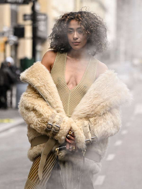 NEW YORK, NEW YORK - FEBRUARY 08: A guest is seen wearing a faux fur cream coat, green sheer net to…