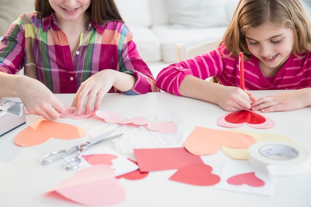 Two girls making heart-shaped valentines.