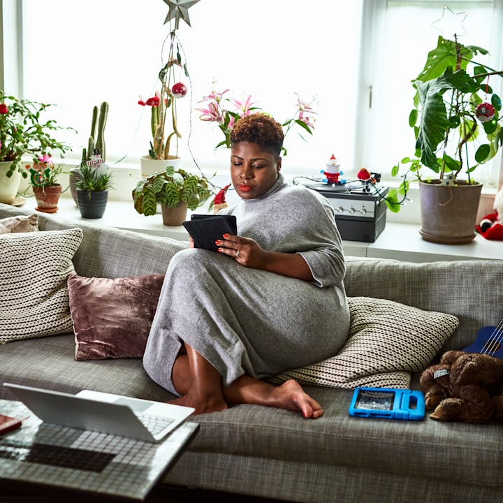 Woman with feet up on comfortable sofa reading tablet at home, comfort, Christmas, freelance work