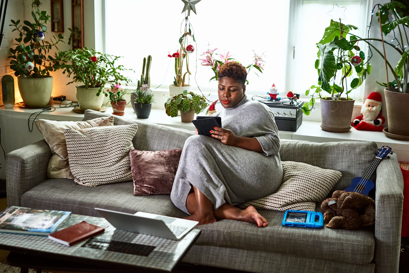 Woman with feet up on comfortable sofa reading tablet at home, comfort, Christmas, freelance work