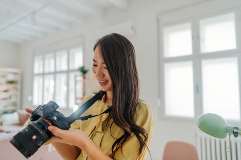 Photo of a Japanese woman checking and testing out her new camera while working in her studio.