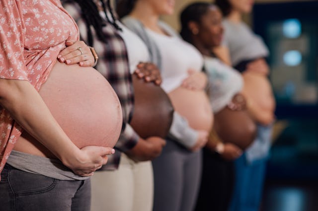 An unrecognisable group of pregnant mothers-to-be standing in a line in a community centre in Seaton...