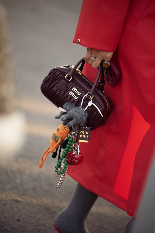 A fashion week guest wears red coat and brown Miu Miu bag
