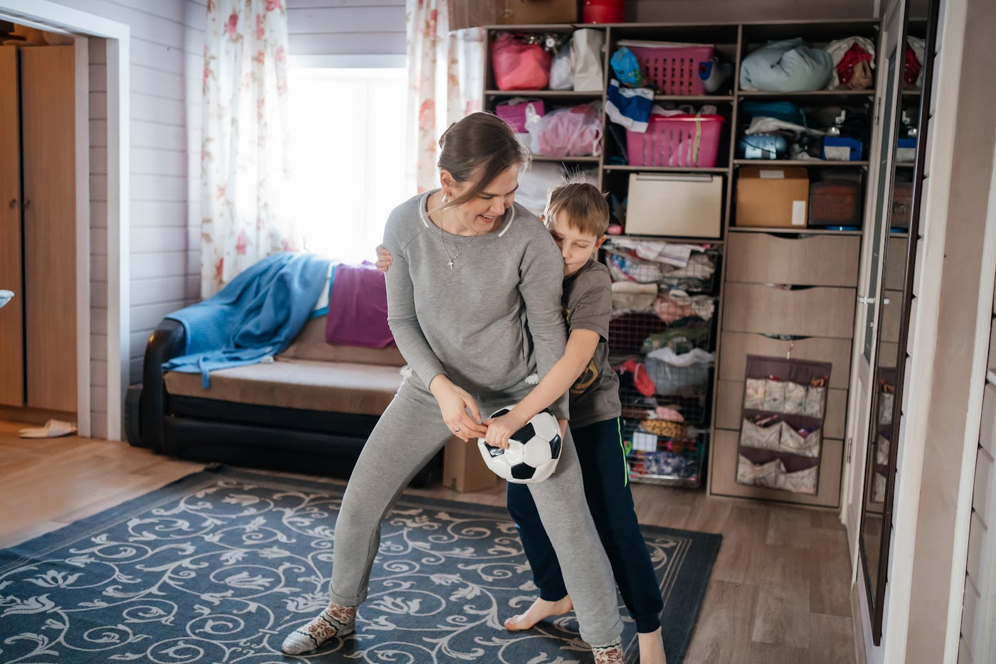 mom has fun playing ball with her child in a cozy house