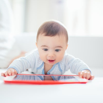A curious baby is engaged with a tablet. Currently, 40% of children have a tablet by age 2.