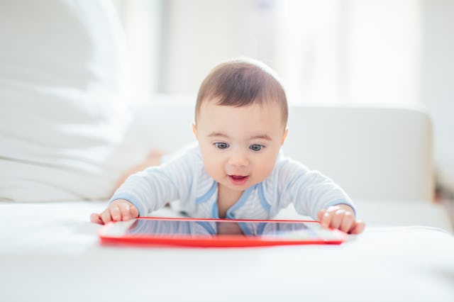 A curious baby is engaged with a tablet. Currently, 40% of children have a tablet by age 2.