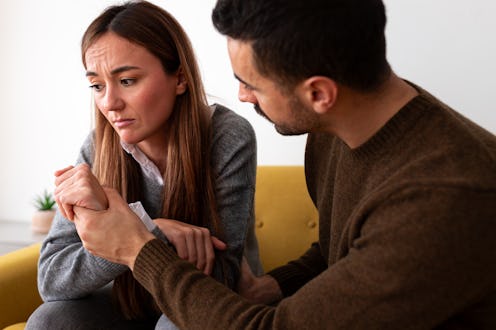 Man consoling sad wife sitting on the sofa at home living room. Lifestyle concept.
