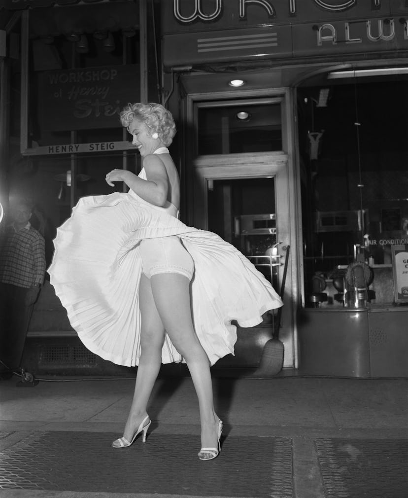 Film star Marilyn Monroe poses over a Manhattan subway grate as the wind blows her white dress up. P…