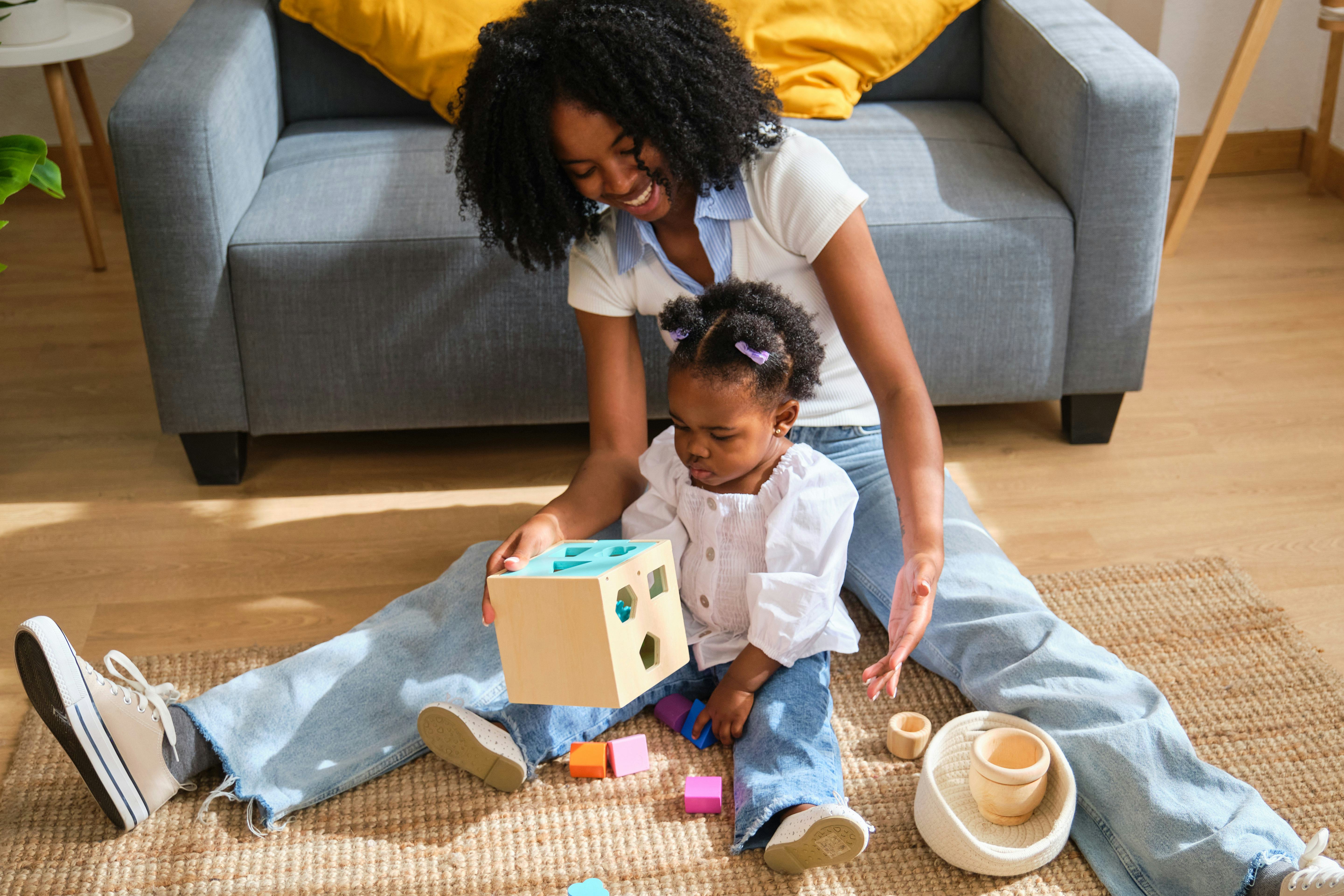 A woman and a child playing with blocks on a rug
