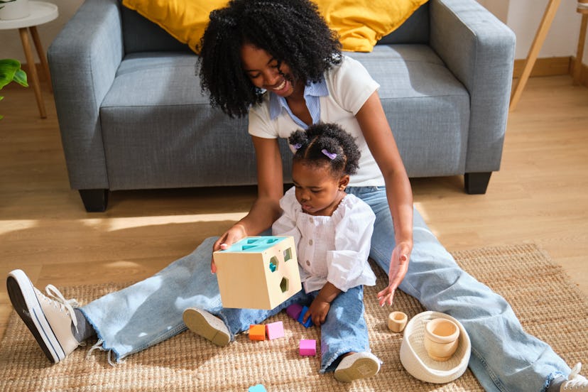 A woman and a child playing with blocks on a rug