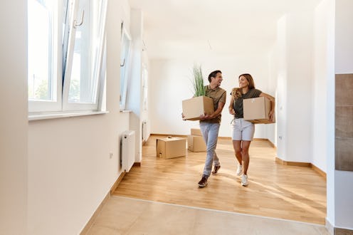 Cheerful couple talking while carrying their belongings in their new home. Copy space.